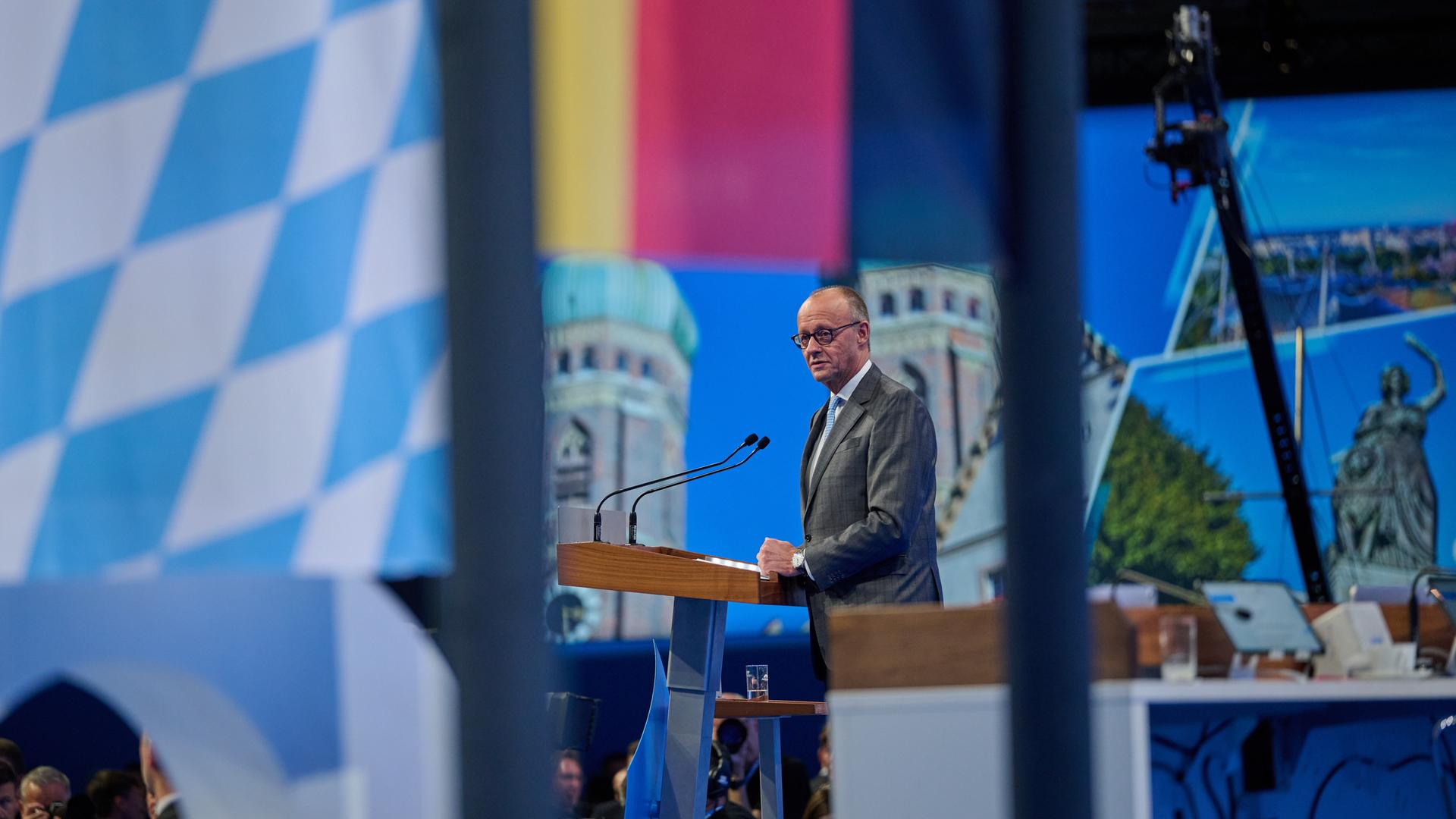 Bundeskanzler Friedrich Merz steht auf einer Bühne. Zu sehen sind die Flaggen Deutschlands und Bayerns.