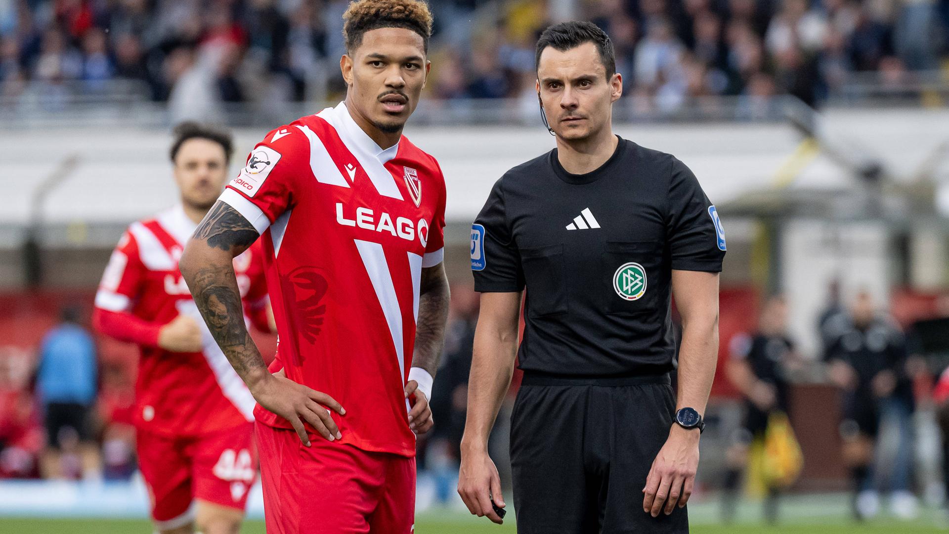 Das Foto zeigt Justin Butler von Energie Cottbus und Schiedsrichter Konrad Oldhafer im Spiel gegen den TSV 1860 München.