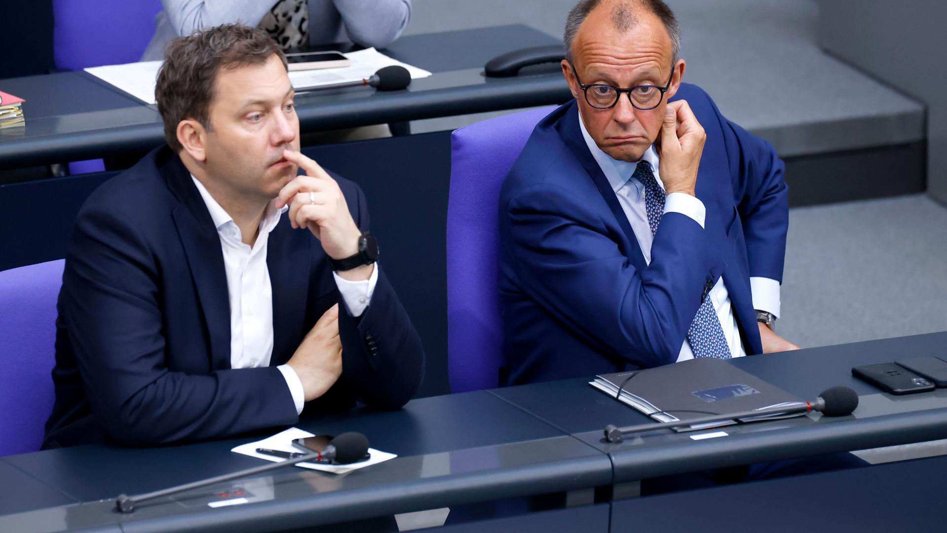 Bundesfinanzminister Lars Klingbeil SPD und Bundeskanzler Friedrich Merz CDU sitzen im Deutschen Bundestages im Reichstagsgebäude in Berlin und schauen nachdenklich