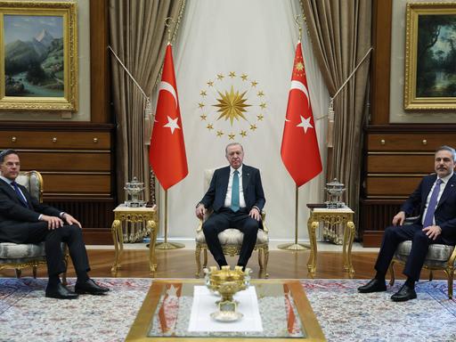 Der türkische Präsidenten Recep Tayyip Erdogan (Mitte), NATO-Generalsekretär Mark Rutte (links) und der türkische Außenminister Hakan Fidan (rechts) bei einem Treffen im Präsidentenpalast in Ankara. Sie sitzen auf goldenen Stühlen.