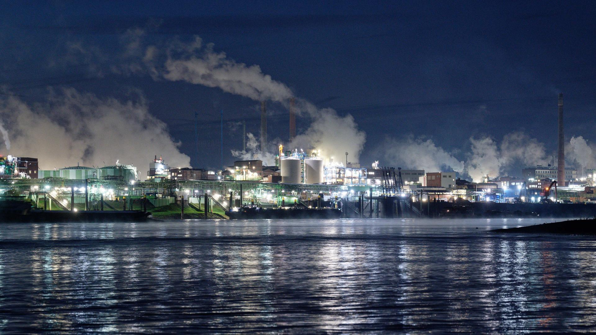 Die Lichter des Chemparks in Leverkusen spiegeln sich im Wasser des Rheins. 