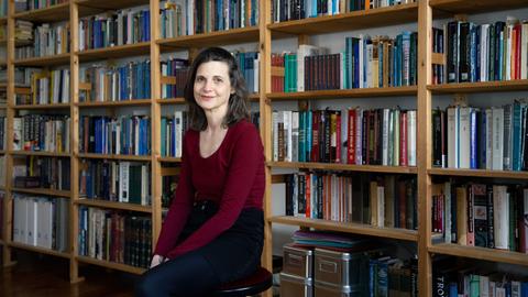 Die Autorin Erica Benner sitzt vor einer Bücherwand.