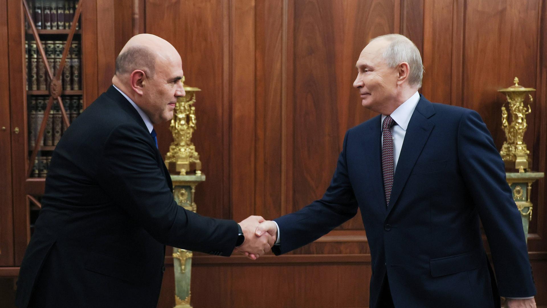 Der russische Präsident Wladimir Putin trifft sich im Kreml in Moskau mit Premierminister Michail Mischustin, sie schütteln sich die Hände. 