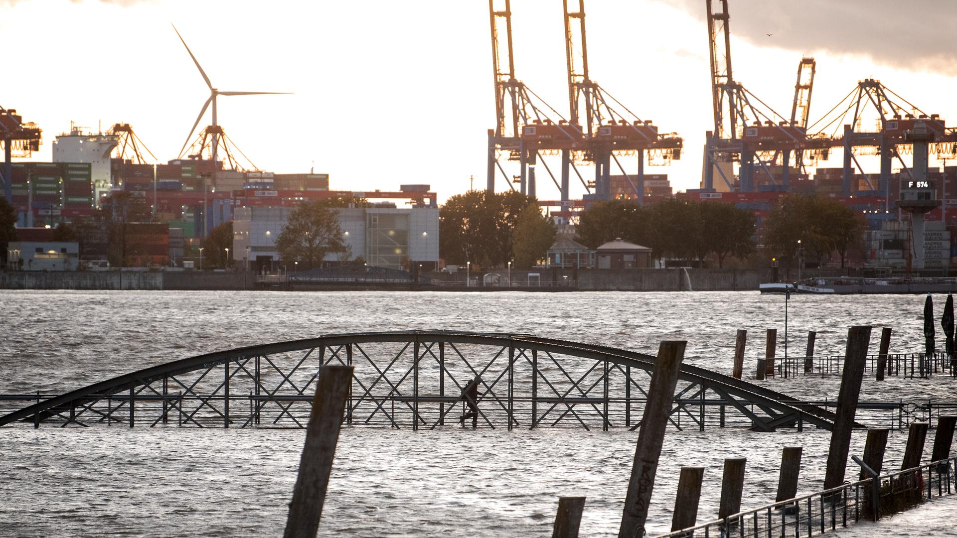 Eine Frau geht am Fischmarkt an der Elbe im Hafen während einer Sturmflut über eine unter Wasser stehende Brücke. Sturmtief „Joshua“ zog im Oktober 2025 als Herbststurm über Deutschland hinweg. Eine Frau geht am Fischmarkt an der Elbe im Hafen während einer Sturmflut über eine unter Wasser stehende Brücke. Sturmtief „Joshua“ zog im Oktober 2025 als Herbststurm über Deutschland hinweg.