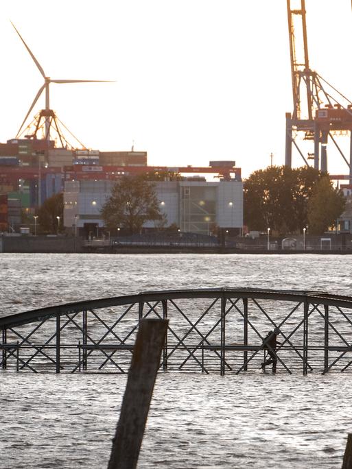 Eine Frau geht am Fischmarkt an der Elbe im Hafen während einer Sturmflut über eine unter Wasser stehende Brücke. Sturmtief „Joshua“ zog im Oktober 2025 als Herbststurm über Deutschland hinweg. Eine Frau geht am Fischmarkt an der Elbe im Hafen während einer Sturmflut über eine unter Wasser stehende Brücke. Sturmtief „Joshua“ zog im Oktober 2025 als Herbststurm über Deutschland hinweg.
