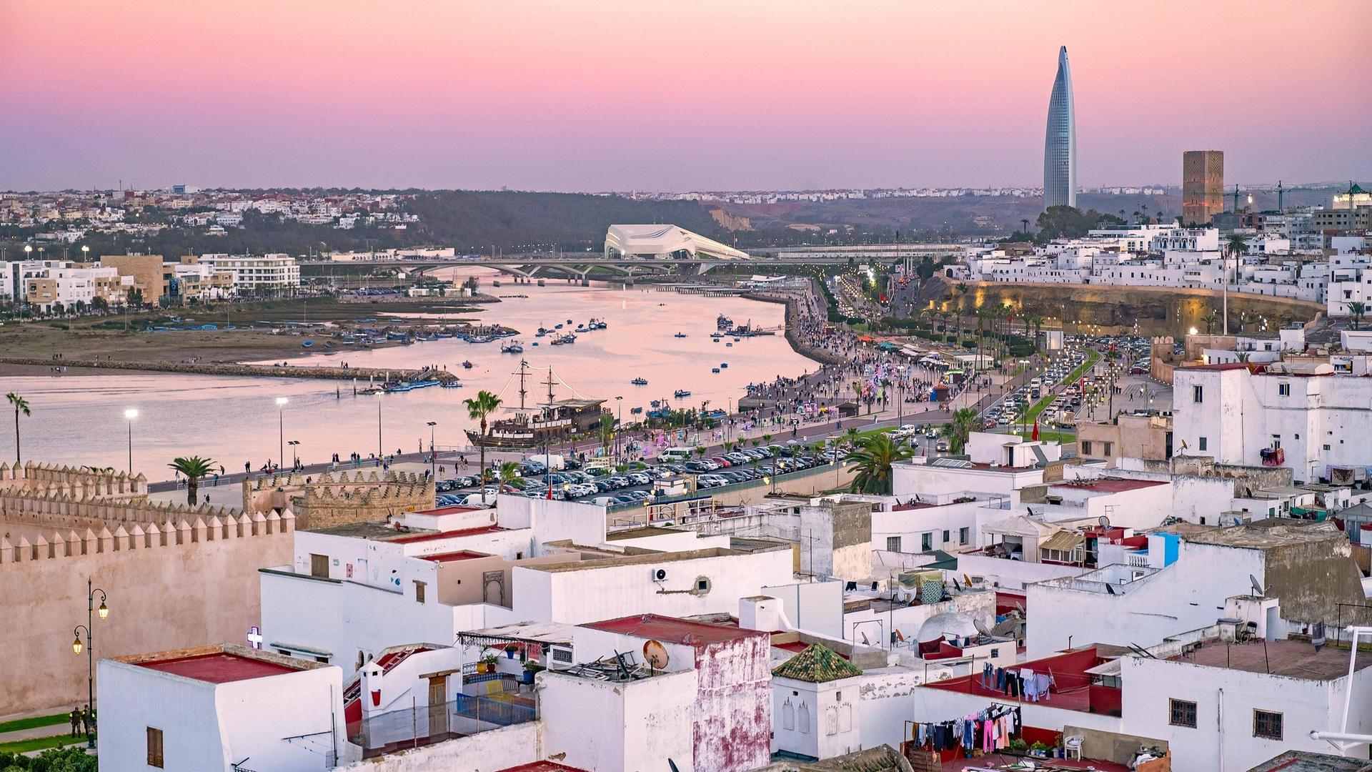 Luftaufnahme über den Fluss Bou Regreg, die Medina, den Hassan Turm und den Mohammed VI Turm in der Stadt Rabat bei Sonnenuntergang Luftaufnahme über den Fluss Bou Regreg, die Medina, den Hassan Turm und den Mohammed VI Turm in der Stadt Rabat bei Sonnenuntergang