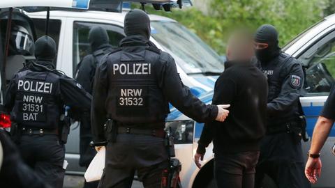 Polizisten nehmen bei einer Razzia im Kampf gegen die organisierte Kriminalität eine verdächtige Person mit. (Archivbild)