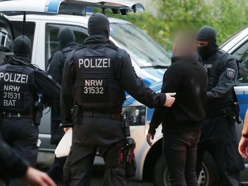 Polizisten nehmen bei einer Razzia eine verdächtige Person mit. Mit Durchsuchungen mehrerer Dutzend Wohnungen und Cafes sind Ermittler gegen organisierte Rauschgiftkriminalität in Nordrhein-Westfalen vorgegangen.