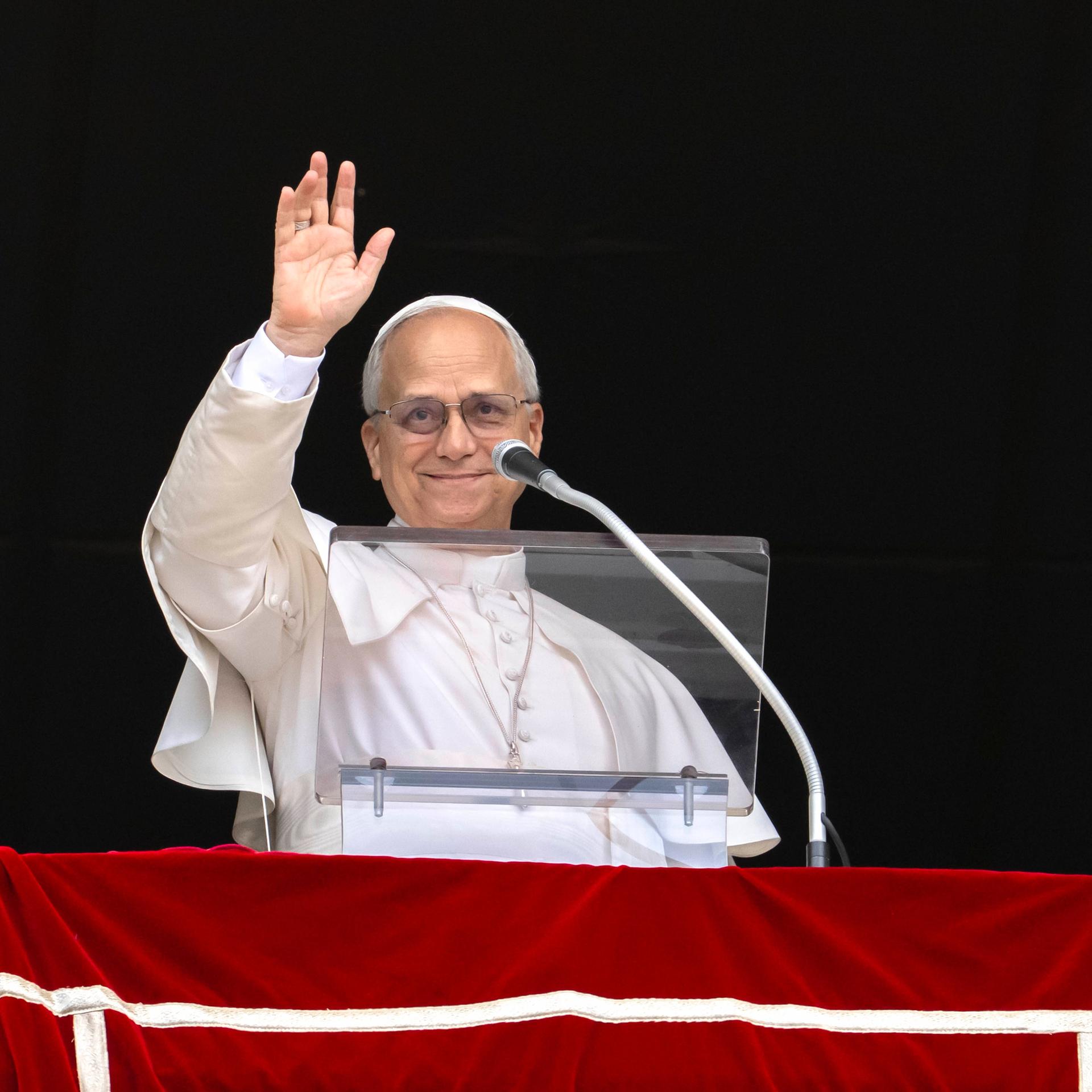 Das Foto zeigt Papst Leo am Fenster, er hält eine Hand zum Gruß hoch. VATICANxMEDIAx