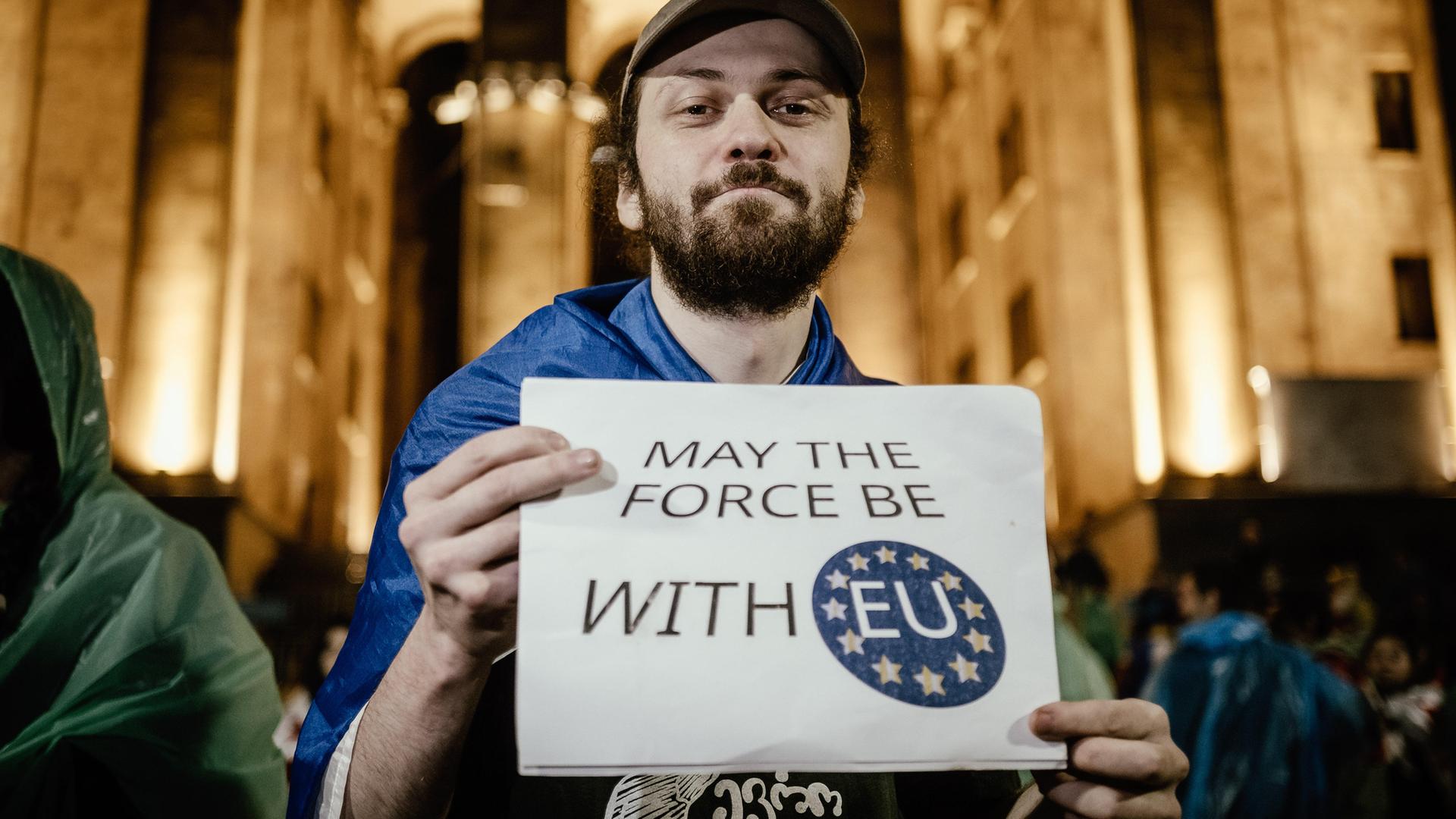 Ein junger Mann hält bei einer Demonstration ein Schild mit der Aufschrift "May the Force with EU" in die Kamera.