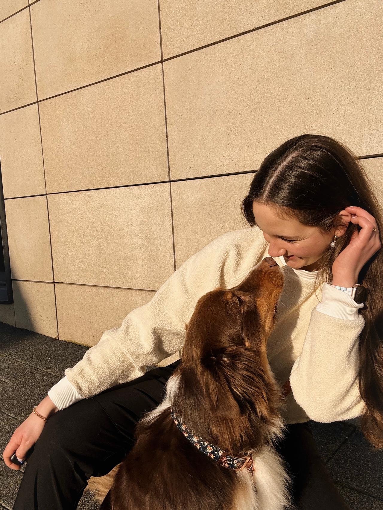 Anna und ihr Hund Bailey vor einer Wand. Sie schauen sich an. Anna lächelt. Anna und ihr Hund Bailey vor einer Wand. Sie schauen sich an. Anna lächelt.