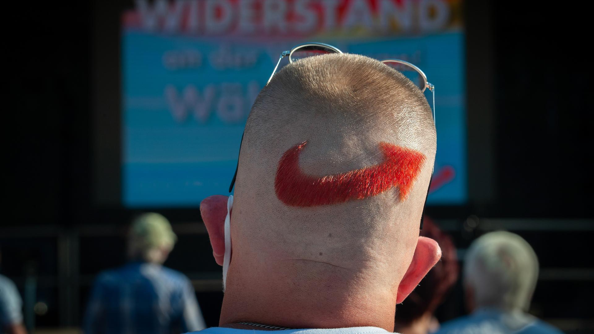 Ein AfD-Anhänger bei einer Veranstaltung der Partei. Auf den Hinterkopf hat er sich das AfD-Parteilogo rasiert und rot gefärbt.