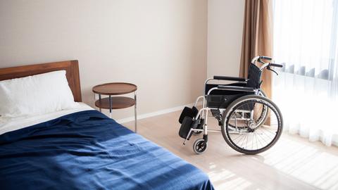 In einem Seniorenheim steht ein leerer Rollstuhl und ein leeres Bett.