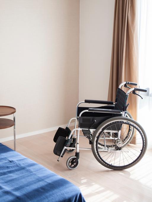 In einem Seniorenheim steht ein leerer Rollstuhl und ein leeres Bett. In einem Seniorenheim steht ein leerer Rollstuhl und ein leeres Bett.