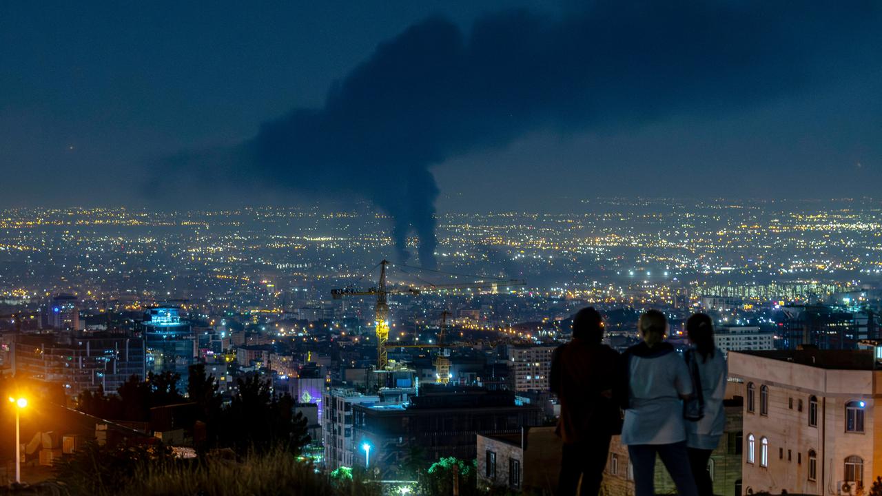 Panorama-Ansicht von Teheran bei Nacht. Über der Stadt ist deutlich eine aufsteigende Rauchsäule zu erkennen.