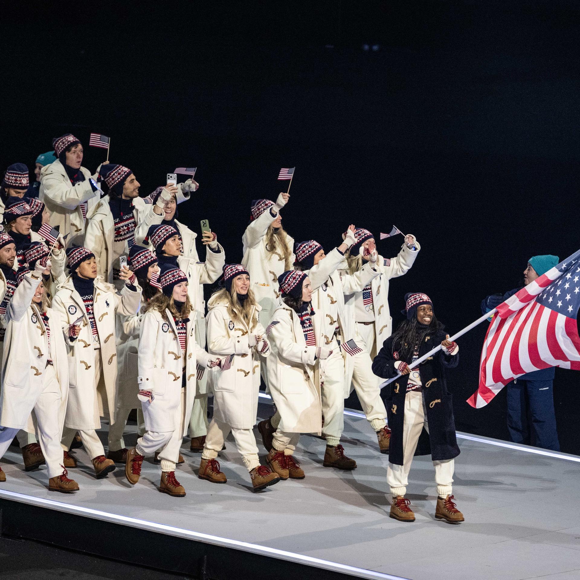 Erin Jackson trägt die amerikanische Fahne und geht vor ihren Teamkollegen bei der Eröffnungsfeier der Olympischen Winterspiele.
