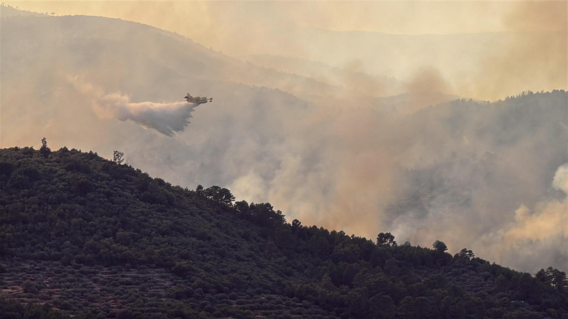 Ein Wasserwerfer-Flugzeug lässt Löschwasser über dem Wald im spanischen Avila ab. Ein Wasserwerfer-Flugzeug lässt Löschwasser über dem Wald im spanischen Avila ab.
