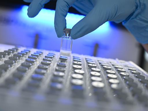 Eine Hand in einem Gummihandschuh entnimmt in einem Labor  des Darmstädter Pharma- und Technologiekonzerns Merck KGaA eine gefriergetrocknete Probe aus einem Behälter. 