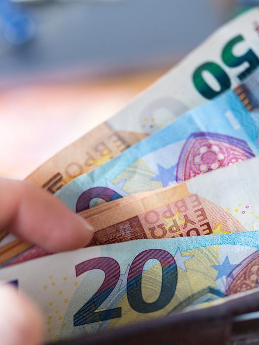 Eine Hand hält eine Geldbörse mit Banknoten