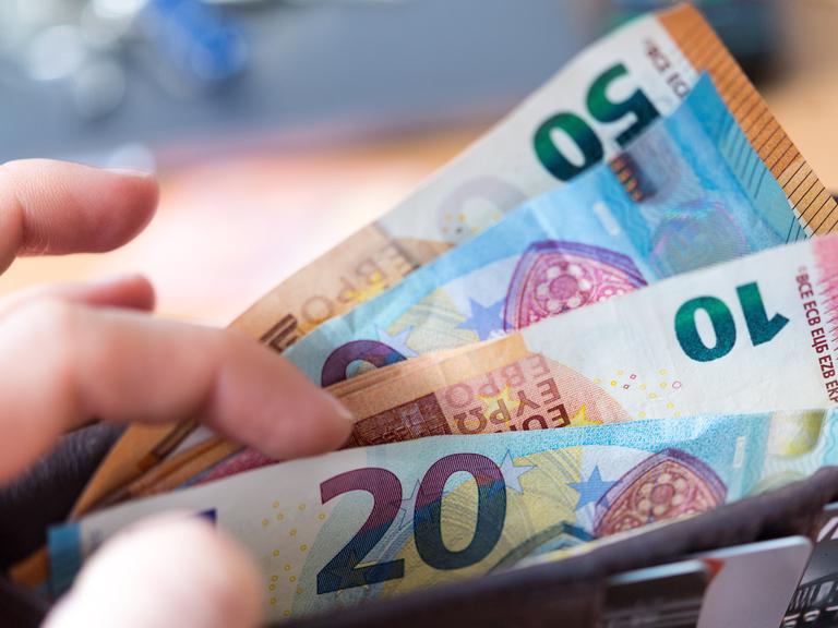 Eine Hand hält eine Geldbörse mit Banknoten