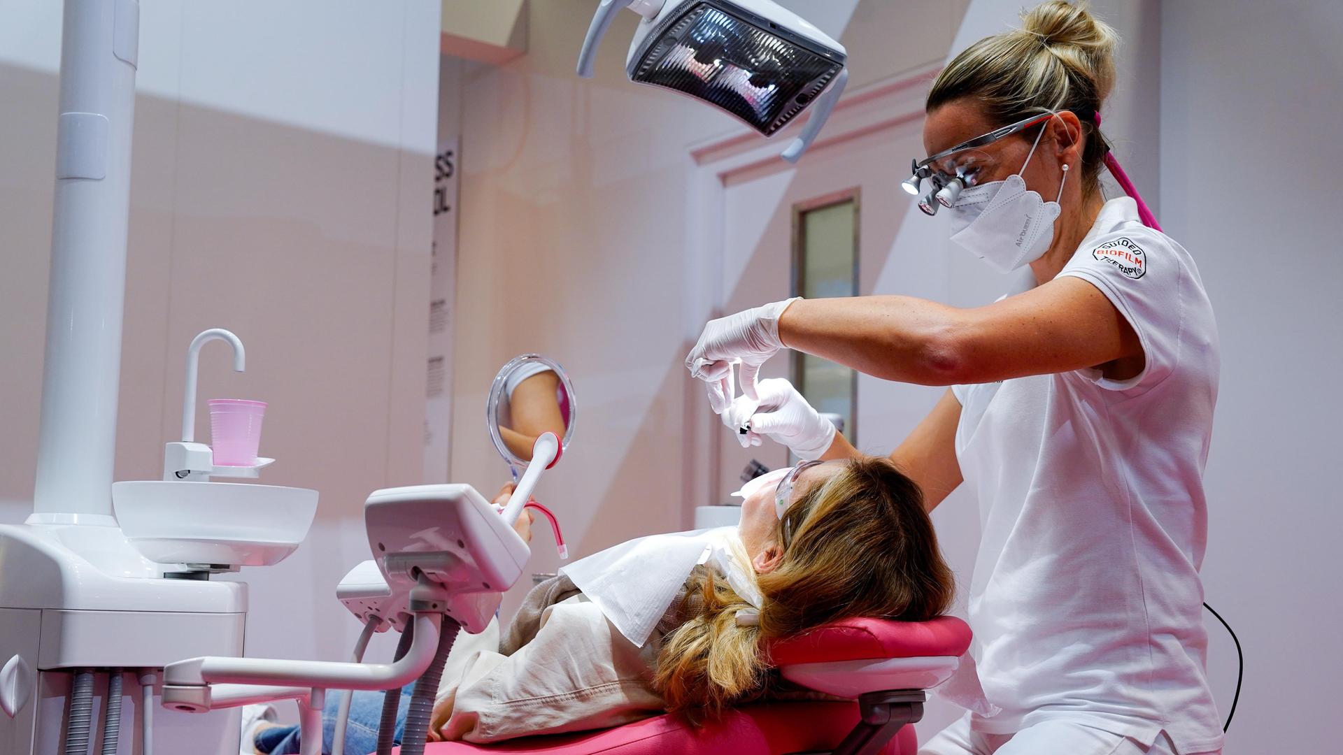 Zahnärztin bei Behandlung eines Patienten auf dem Zahnarztstuhl