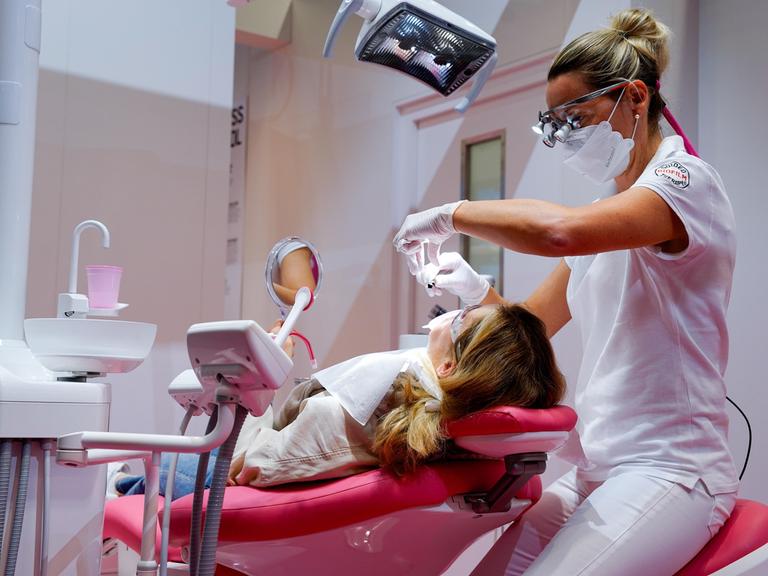 Zahnärztin bei Behandlung eines Patienten auf dem Zahnarztstuhl