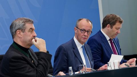 Bundeskanzler Friedrich Merz (CDU/M.), Lars Klingbeil (SPD,r.), Bundesfinanzminister, und Markus Söder (CSU/l.), Ministerpräsident des Freistaats Bayern, sitzen während einer Pressekonferenz im Kanzleramt nebeneinander an einem Tisch