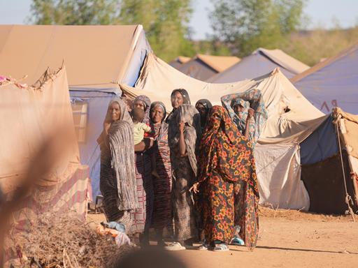 Mehrere Frauen im Flüchtlingslager Goz al-Haj blicken skeptisch in die Kamera, im Hintergrund Zelte. 