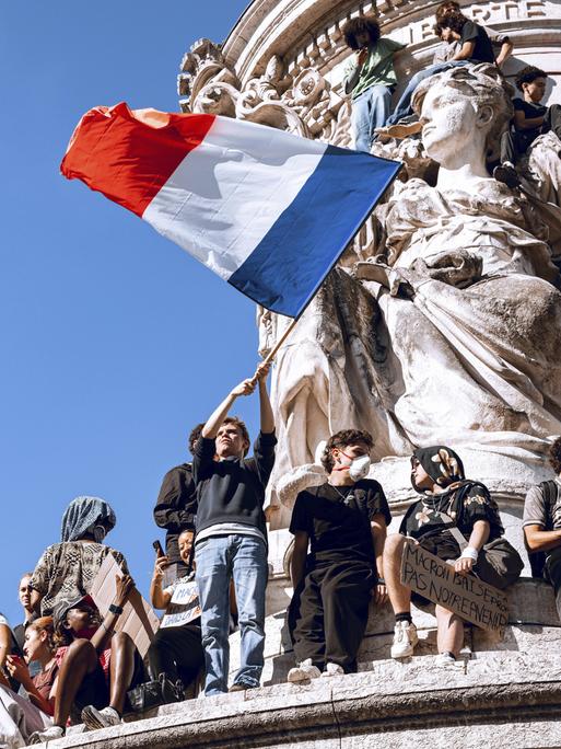 Demonstranten auf der Statue der Republik in Paris schwenken eine große Frankreich-Flagge. Demonstranten auf der Statue der Republik in Paris schwenken eine große Frankreich-Flagge.