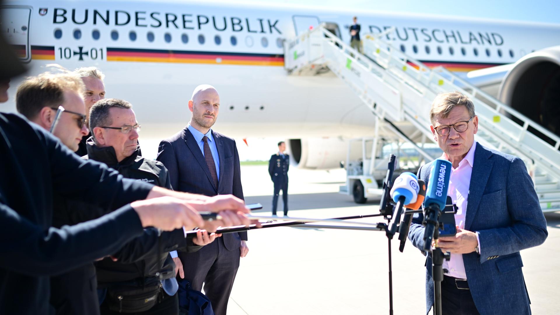 Johann Wadephul (CDU, r), Außenminister, spricht auf dem militärischen Teil des Flughafens Berlin Brandenburg an einem Flugzeug der Flugbereitschaft zu den Medien.