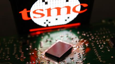 Das Logo des Halbleiterhersteller TSMC in hellem Rot steht über einem Mikrochip.