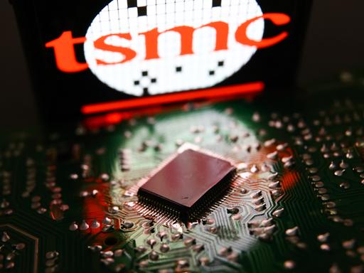 Das Logo des Halbleiterhersteller TSMC in hellem Rot steht über einem Mikrochip.