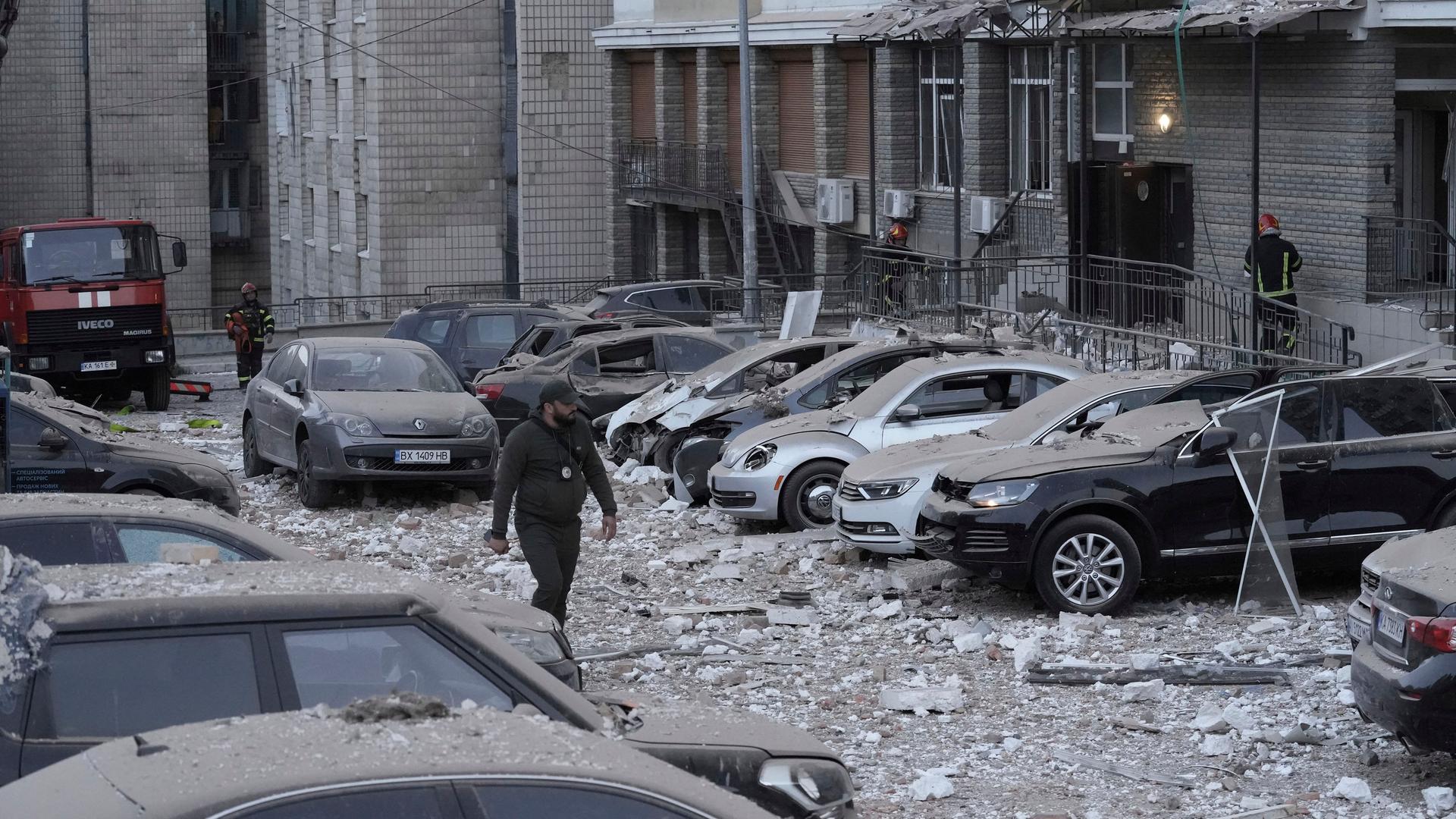 30.05.2023 Kiew: Ein Polizist geht auf dem Parkplatz mit beschädigten Autos vor einem mehrstöckigen Wohnhaus spazieren, das bei einem russischen Angriff in Kiew, Ukraine beschädigt wurde. 