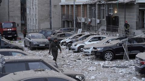 Kiew: Ein Polizist geht auf dem Parkplatz mit beschädigten Autos vor einem mehrstöckigen Wohnhaus spazieren, das bei einem russischen Angriff in Kiew, Ukraine beschädigt wurde.