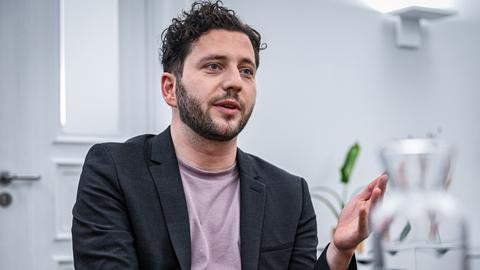 Grünen-Bundesvorsitzender Felix Banaszak sitzt in einem hellem Raum spricht und gestikuliert mit der linken Hand
