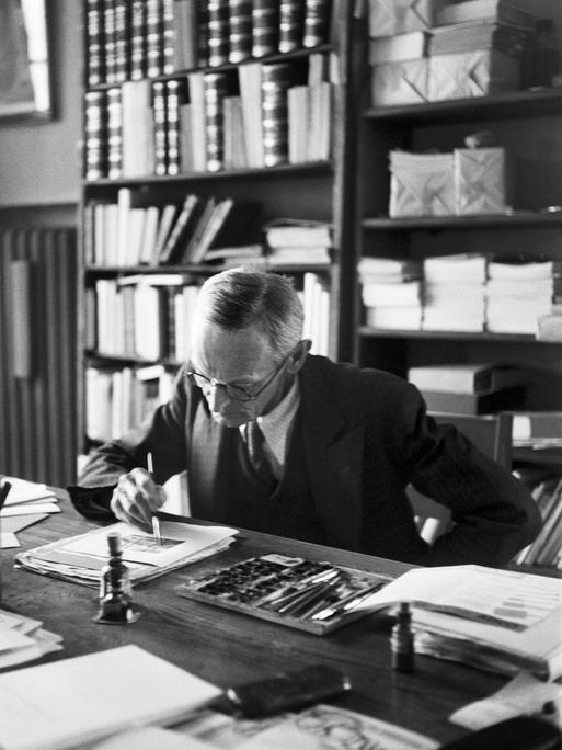 Der Schriftsteller Hermann Hesse arbeitet an einer Illustration im Arbeitszimmer seinen Hauses in Montagnola, Tessin, undatierte Aufnahme. Der Schriftsteller Hermann Hesse arbeitet an einer Illustration im Arbeitszimmer seinen Hauses in Montagnola, Tessin, undatierte Aufnahme.