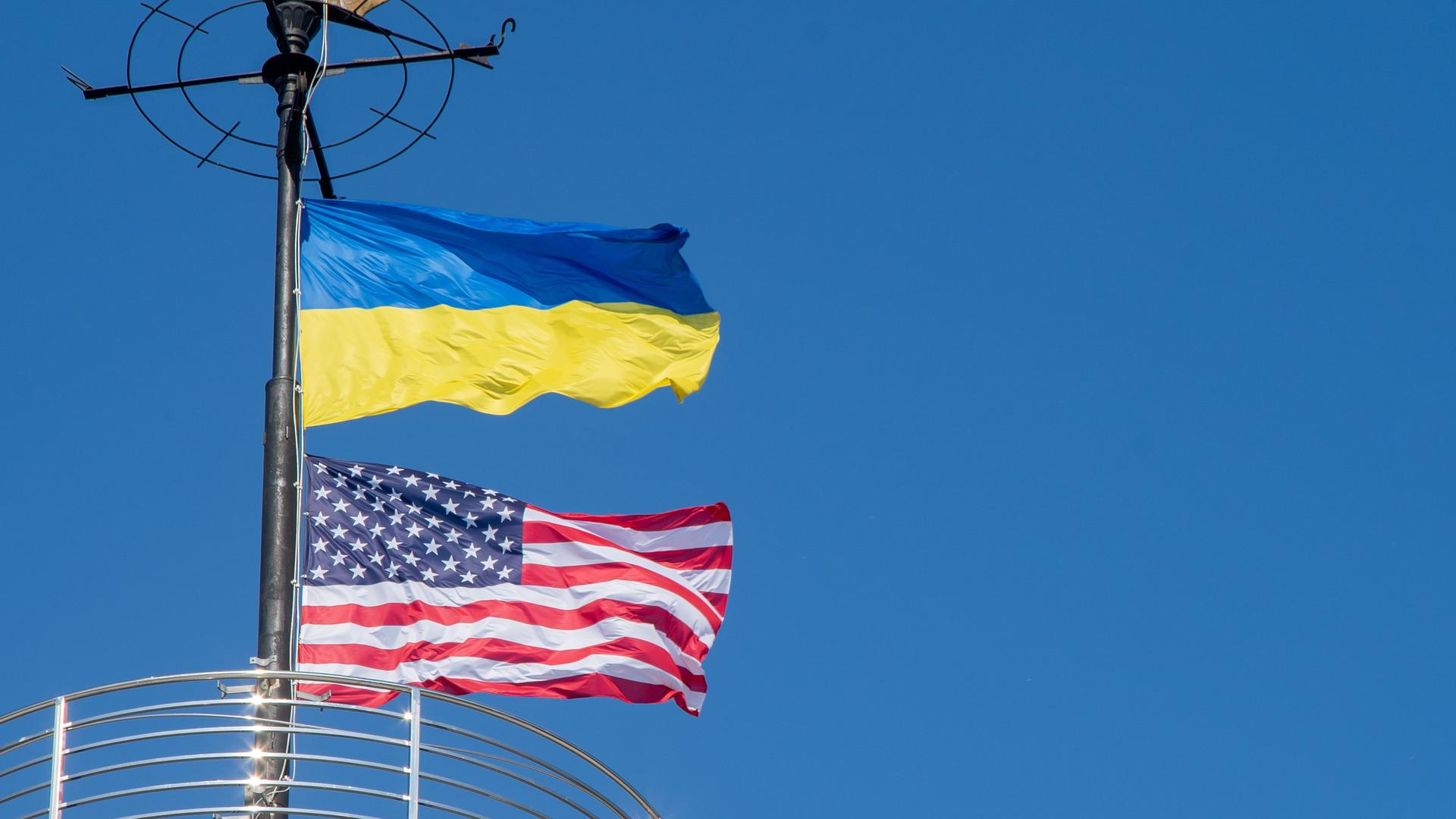 Die ukrainische und die US-amerikanische Flagge wehen untereinander an einem Mast.