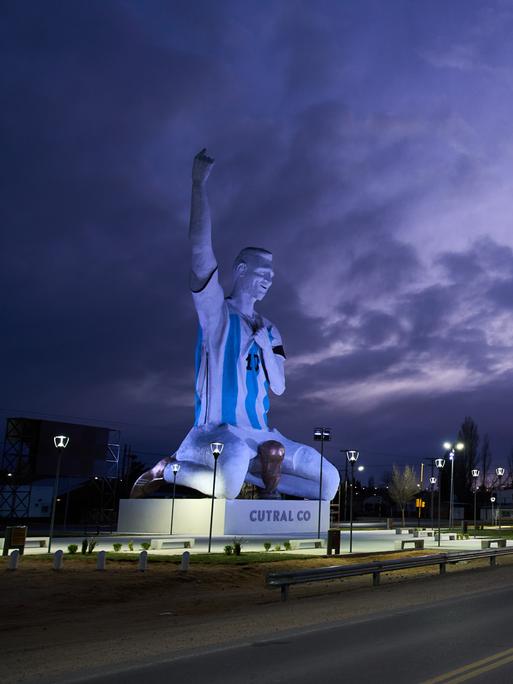 Eine Statue des Fußballspielers Lionel Messi. Er kniet jubelnd, vor sich steht der WM-Pokal.