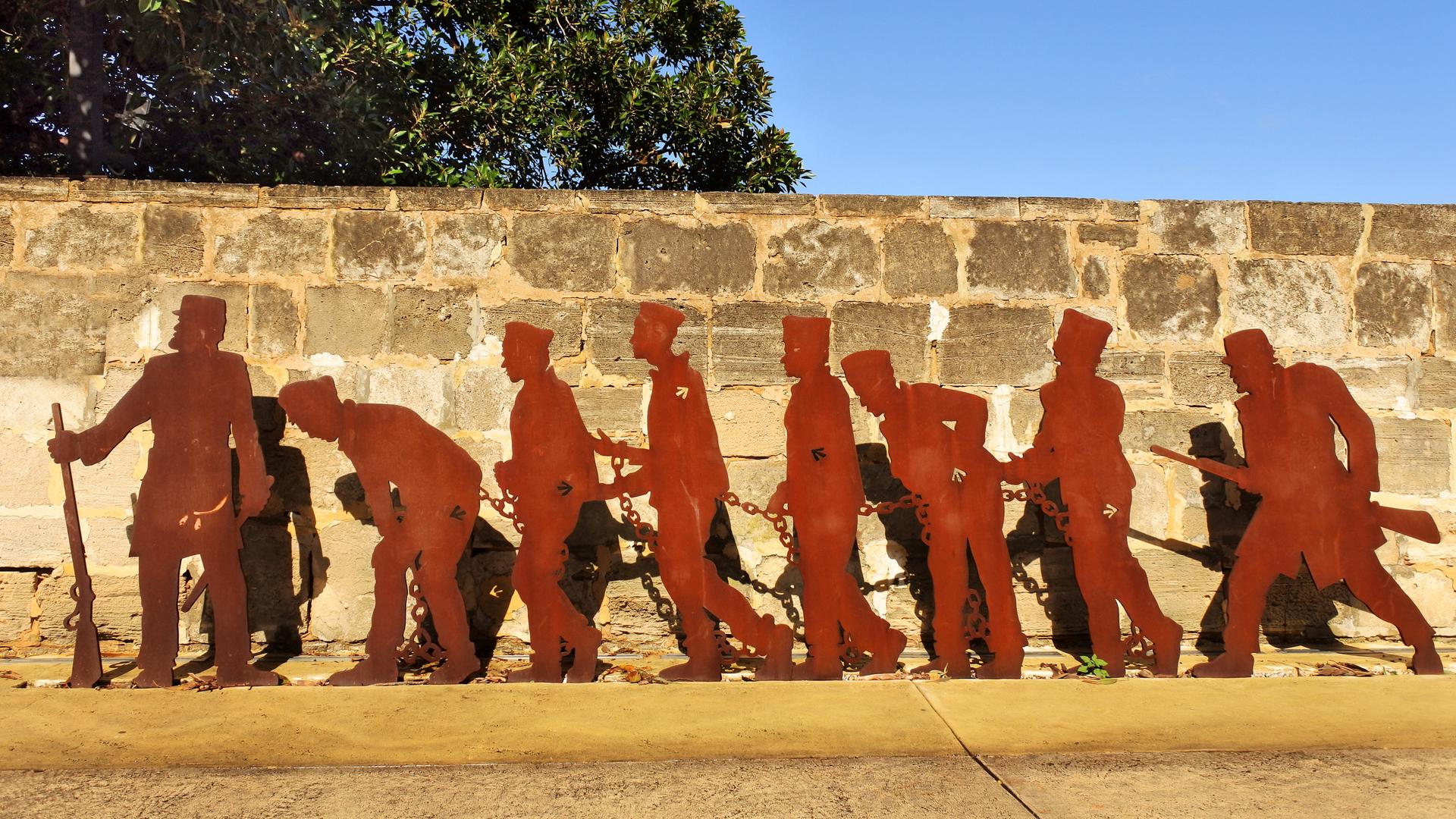 Ein Denkmal mit Umrissen von Gefangenen in Ketten und ihre Bewachern