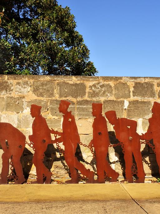 Ein Denkmal mit Umrissen von Gefangenen in Ketten und ihre Bewachern