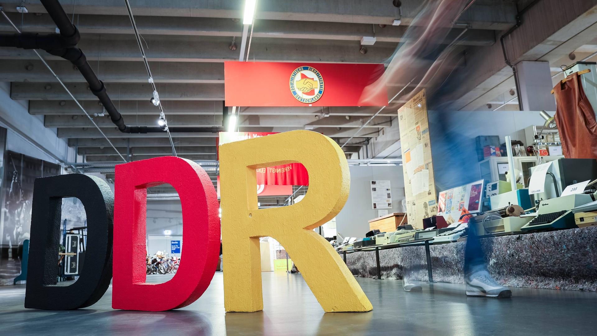 Blick auf Ausstellungsstücke im DDR-Museum in Dresden mit den drei großen Buchstaben DDR links im Vordergrund