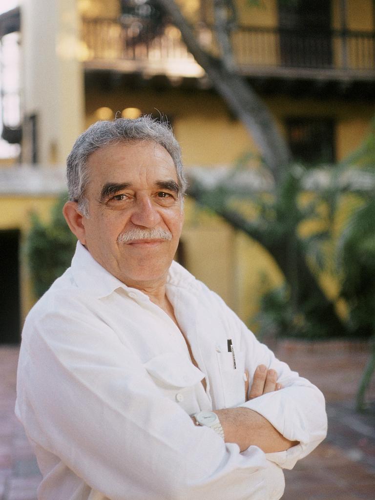 Portrait von Gabriel Garcia Marquez der vor einem gelben Gebäude in einem Innenhof mit Bäumen steht.