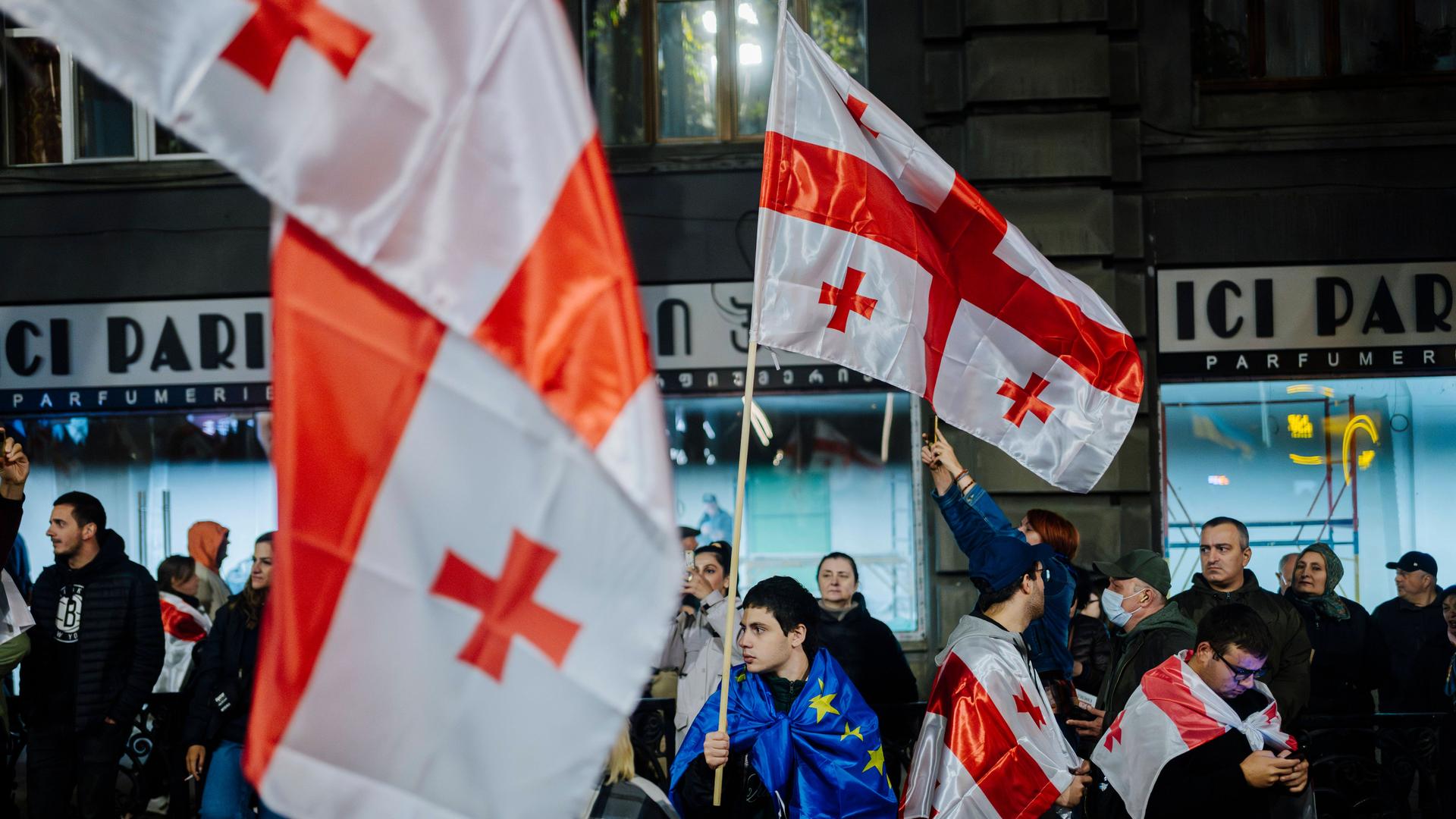 Pro-europäische Kundgebung in Tiflis: Junger Mann in EU-Flagge gehüllt hält eine Georgien-Flagge in der Hand. (20.10.2024)