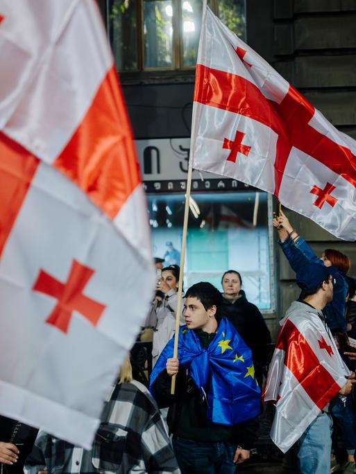 Pro-europäische Kundgebung in Tiflis: Junger Mann in EU-Flagge gehüllt hält eine Georgien-Flagge in der Hand. (20.10.2024)