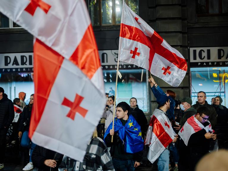 Pro-europäische Kundgebung in Tiflis: Junger Mann in EU-Flagge gehüllt hält eine Georgien-Flagge in der Hand. (20.10.2024)