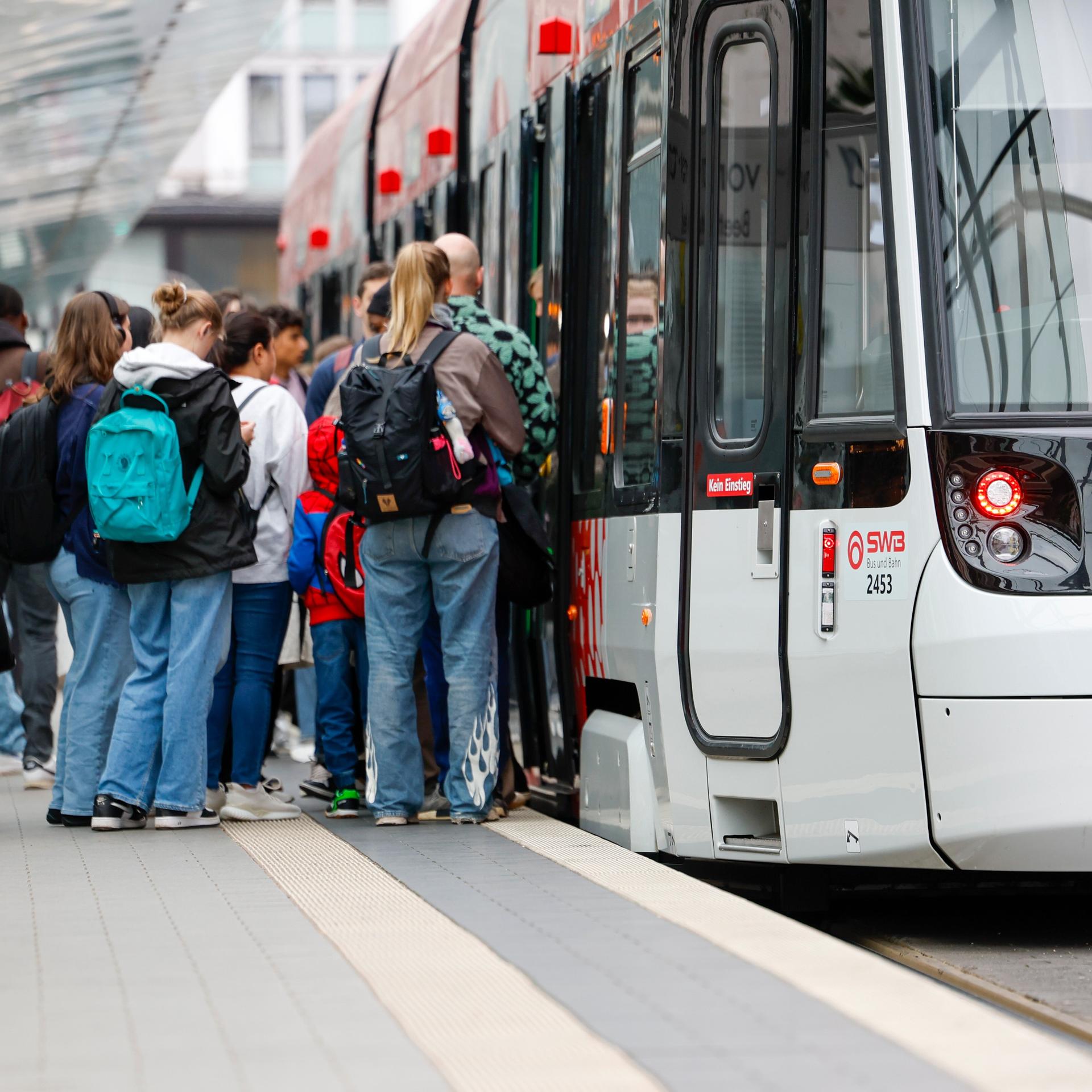 Menschen steigen an der Haltestelle Bertha-von Suttner-Platz in die Straßenbahn der SWB (Stadtwerke Bonn) ein.