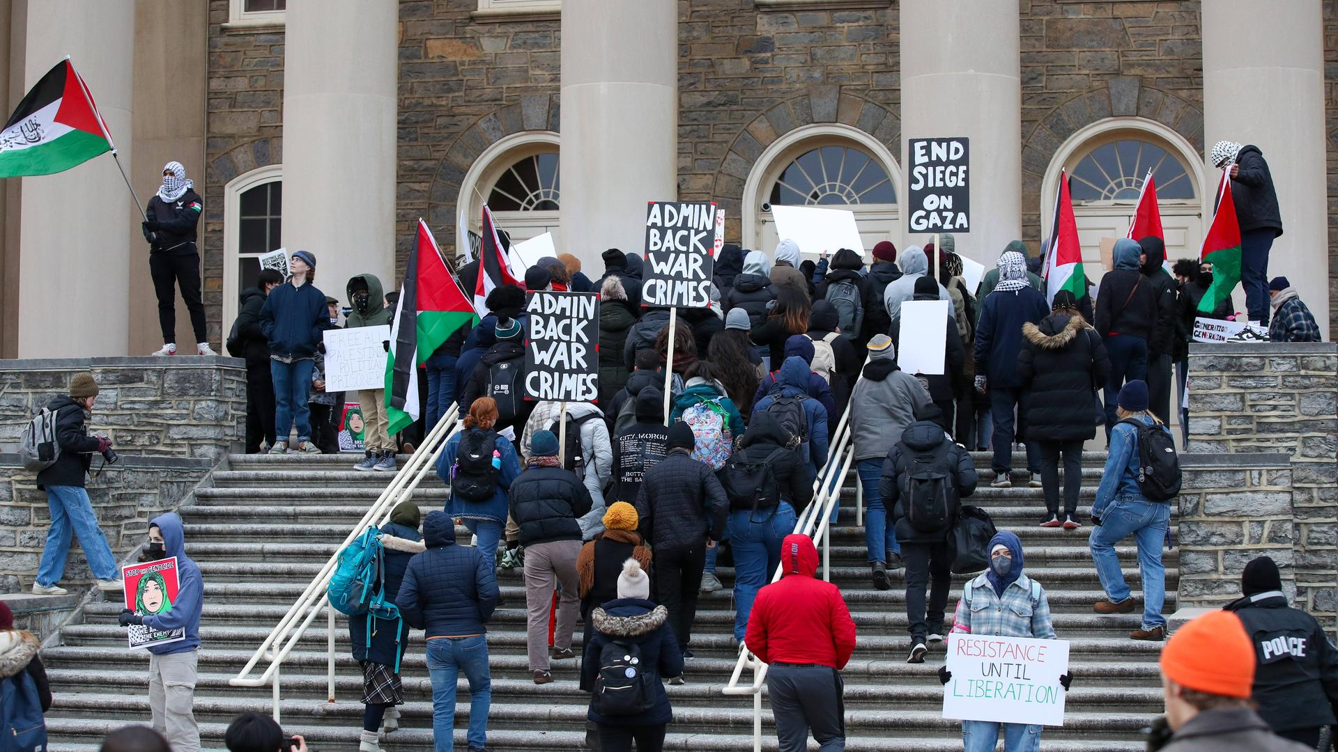 "Admin Back War Crimes": Menschen demonstieren mit Schildern auf den Stufen der der Pennsylvania State University.