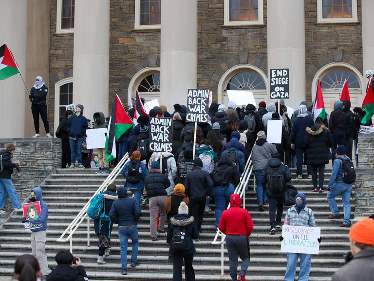 "Admin Back War Crimes": Menschen demonstieren mit Schildern auf den Stufen der der Pennsylvania State University.