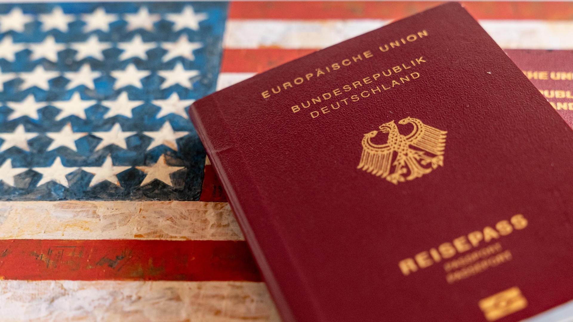 Zwei deutsche Reisepässe liegen auf einem Hintergrund mit der amerikanischen Flagge