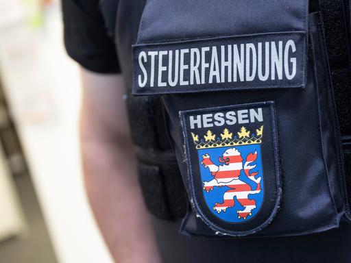 Im Rahmen einer Großrazzia gegen Schwarzarbeit durchsuchen Beamte des Zoll Firmenräume in Frankfurt. Dabei steht ein Beamter der Steuerfahndung bereit.